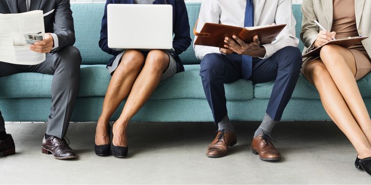 Geschäftsleute sitzen in Reihe mit verschiedenen Publikationen